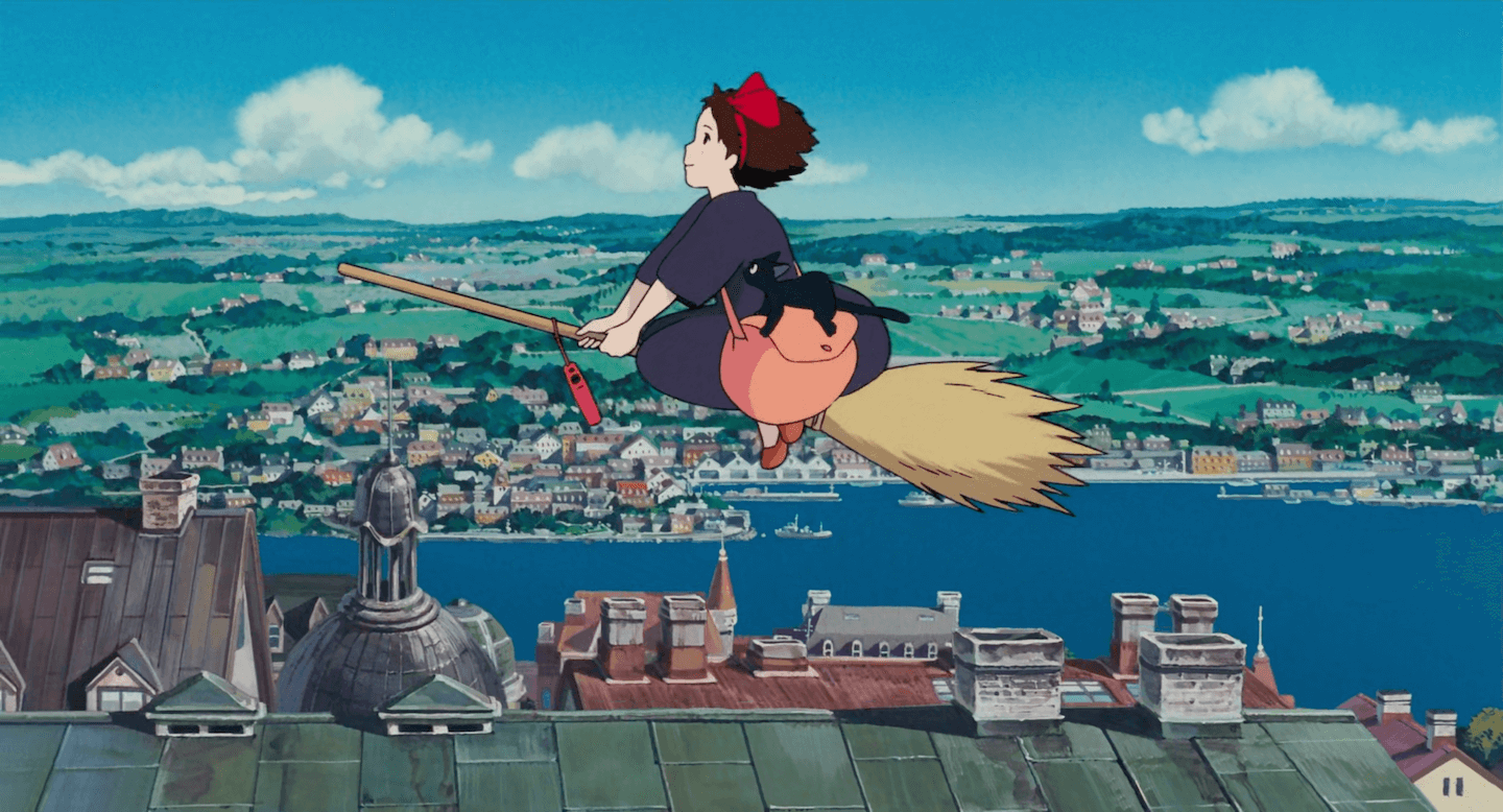 Image of Kiki soaring above rooftops on a broomstick